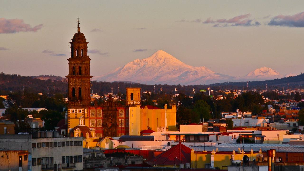Puebla es un estado ubicado en el centro de México, conocido por su impresionante arquitectura colonial, su rica historia y su gastronomía única. Su capital, **Puebla de Zaragoza**, es famosa por su **Centro Histórico**, declarado Patrimonio de la Humanidad, y por su **Catedral** y el **Zócalo**. Puebla también es hogar de las **Cholula**, con su imponente pirámide, la más grande de América Latina. Su gastronomía es mundialmente conocida, con platillos emblemáticos como el **mole poblano**, las **chalupas**, y las **cemitas**. Además, Puebla es famosa por sus **talavera** (cerámica pintada a mano) y su cercanía al **Popocatépetl**, uno de los volcanes más activos de México.